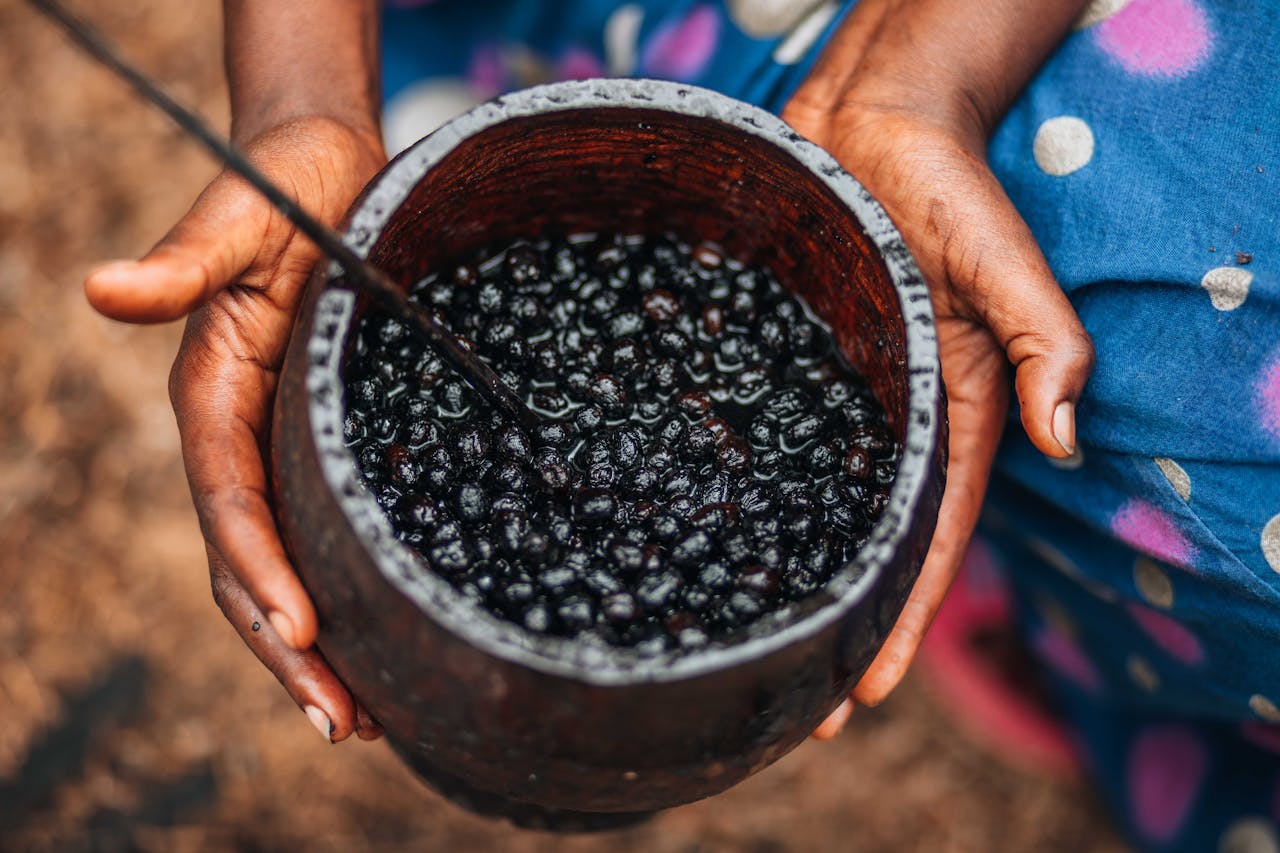 hero-img-02 Close-up of a woman holding a bowl of fresh açaí berries, emphasizing natural texture and color.